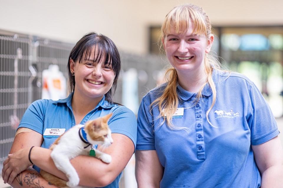 Two AHS team members holding a white and orange cat at the Woodbury adoption center.