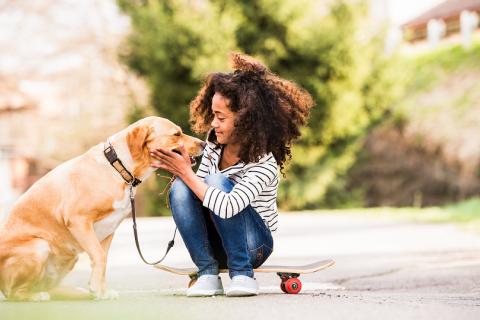 Girl sitting on skateboard with a yellow lab